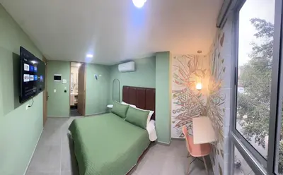 a room with a green couch and a window at Amaranto Suites in Medellín