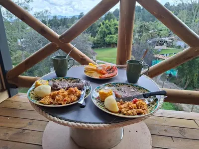 a table with three plates of food on a balcony at Alma Cabañas y Spa in Guarne