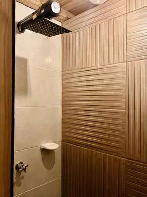 a bathroom with a shower with a wooden wall at Alma Cabañas y Spa in Guarne