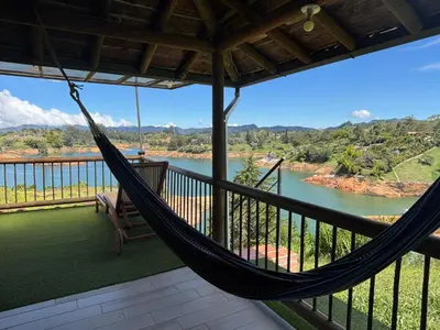a hammock on a balcony with a view of a river at Loge Cabaña peñol-Guatape in El Peñol