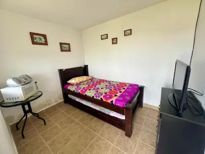 a small bedroom with a bed and a tv at Loge Cabaña peñol-Guatape in El Peñol