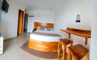 a bedroom with a wooden bed and a desk at Hotel Las Vegas in Rionegro