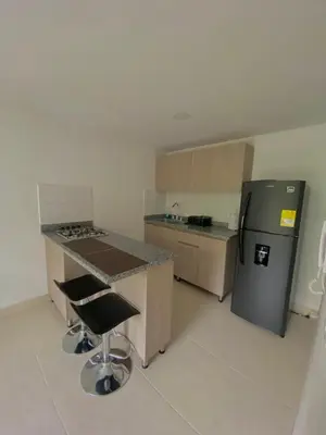a kitchen with a counter and a refrigerator and a stool at Apartamento Urban Manizales in Manizales