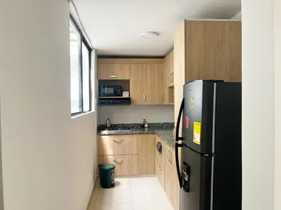 a kitchen with a black refrigerator and wooden cabinets at Loft dreams 7005 in Medellín