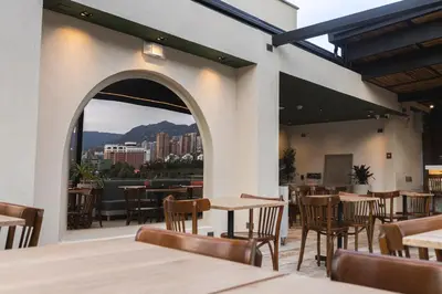 a restaurant with tables and chairs and a view of the city at Sloh Hotel & Bar Manila Medellin in Medellín