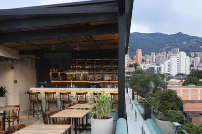a restaurant with tables and chairs and a view of the city at Sloh Hotel & Bar Manila Medellin in Medellín