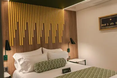 a bedroom with a bed with a wooden headboard at Sloh Hotel & Bar Manila Medellin in Medellín