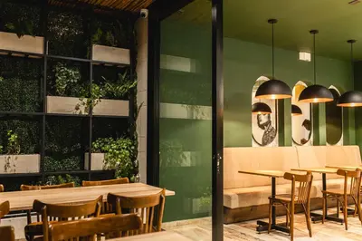 a restaurant with green walls and wooden tables and chairs at Sloh Hotel & Bar Manila Medellin in Medellín