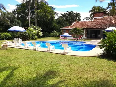 a pool with chairs and an umbrella in a yard at Villa Privada con entrada y salida 100 por ciento flexible in La Florida
