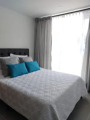 a bedroom with a bed with blue pillows and a window at Brand New Apartment Manizales in Manizales