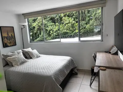 a bedroom with a bed and a large window at Cálido mini apartamento in Manizales