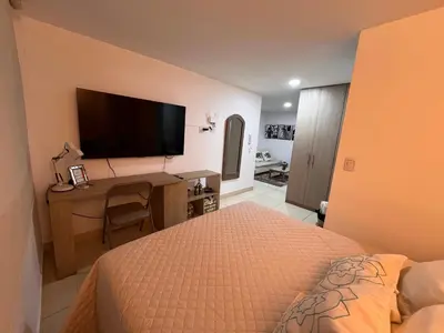 a bedroom with a bed and a desk with a flat screen tv at Cálido mini apartamento in Manizales