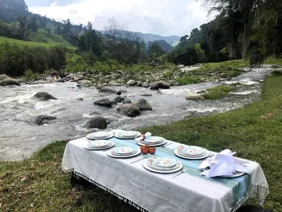 a table with plates on it next to a river at Alojamiento con vista al río y paisajes hermosos in Manizales