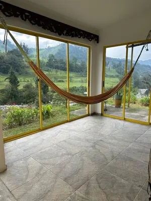 a room with a hammock in front of windows at Alojamiento con vista al río y paisajes hermosos in Manizales