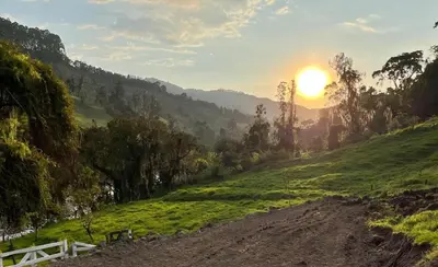 a dirt road with the sun setting on a hill at Alojamiento con vista al río y paisajes hermosos in Manizales