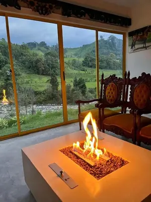 a fire pit in a living room with a large window at Alojamiento con vista al río y paisajes hermosos in Manizales