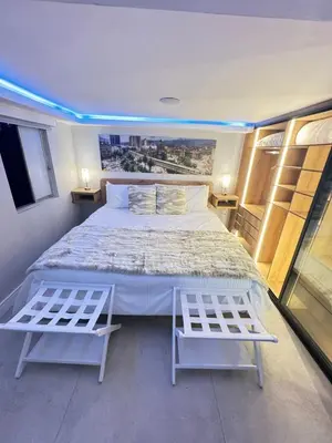 a bedroom with a large bed and two white chairs at Luxury Apartment Jacuzzi Air Conditioning Fireplace and King Bed in Medellín
