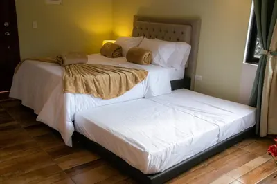 two beds in a bedroom with white sheets and pillows at Loft para grupos parqueadero gratis LIRIO in Jardin