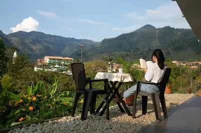 a woman sitting at a table with a view of mountains at Loft para grupos parqueadero gratis LIRIO in Jardin