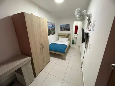 a small bedroom with a bed and a refrigerator at Habitación individual privada con baño privado y desayuno in Medellín
