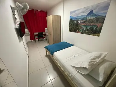 a bedroom with a bed with a painting on the wall at Habitación individual privada con baño privado y desayuno in Medellín