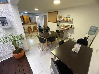 a dining room with tables and chairs and a kitchen at Habitación individual privada con baño privado y desayuno in Medellín