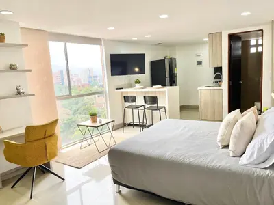a bedroom with a large bed and a kitchen at Modern furnished loft in el Poblado in Medellín