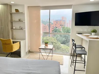 a bedroom with a bed and a desk with chairs at Modern furnished loft in el Poblado in Medellín