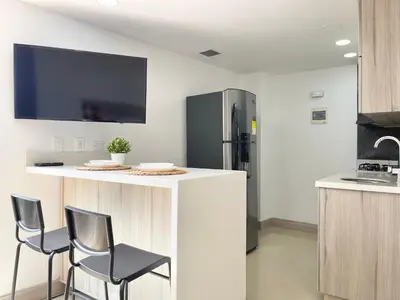 a kitchen with a counter with chairs and a refrigerator at Modern furnished loft in el Poblado in Medellín