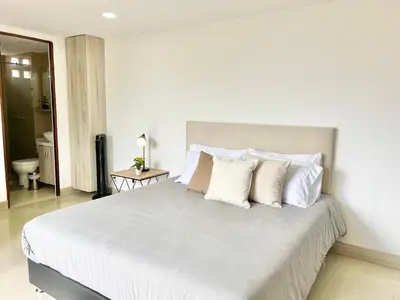 a bedroom with a large bed with white sheets and pillows at Modern furnished loft in el Poblado in Medellín
