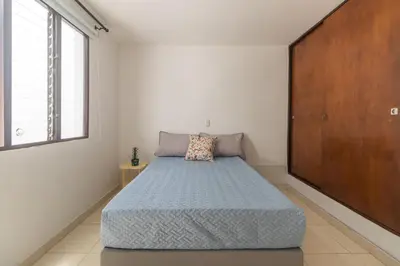 a bedroom with a bed and a large window at Casa de las Flores en Medellín in Medellín