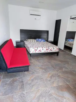 a bedroom with a bed and a red couch at Paraíso in San Jerónimo