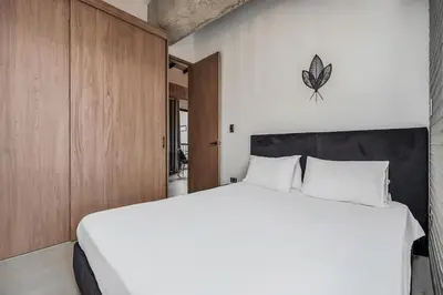 a bedroom with a large white bed and wooden cabinets at Poblado, 5 min to San Lucas Plaza, Free parking 315 in Medellín