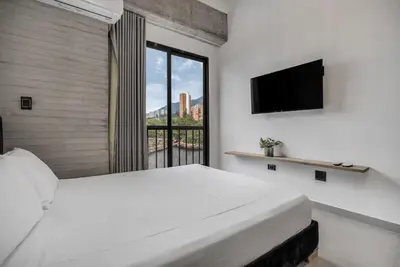 a white bedroom with a large bed and a window at Poblado, 5 min to San Lucas Plaza, Free parking 315 in Medellín