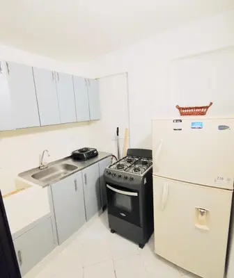 a small kitchen with a stove and a refrigerator at Laureles estadio plaza mayor la 70 unicentro in Medellín
