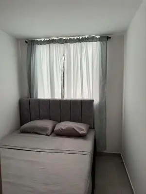 a bed with two pillows in front of a window at Apartamento familiar y agradable in Manizales