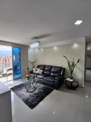 a living room with a black leather couch and a table at RentalsOP AN09 Apartamento en Laureles el barrio mas cool del mundo, moderno, con balcon y excelente vista in Medellín