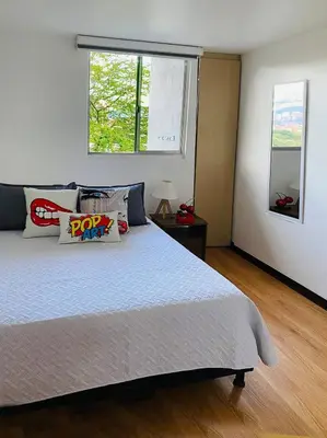 a bedroom with a large bed and a window at Tu hogar temporal en Medellín, Moderno, cómodo, bien ubicado y WIFI 400 in Medellín