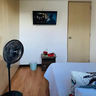 a bedroom with a fan and a tv on the wall at Tu hogar temporal en Medellín, Moderno, cómodo, bien ubicado y WIFI 400 in Medellín