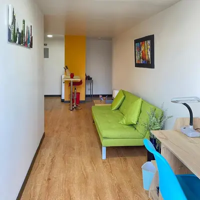 a living room with a green couch and a table at Tu hogar temporal en Medellín, Moderno, cómodo, bien ubicado y WIFI 400 in Medellín