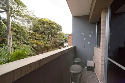 a balcony with two stools and a wall with birds on it at Diseño único y encanto en un barrio tranquilo, in Medellín