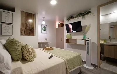 a bedroom with a bed and a tv on the wall at Diseño único y encanto en un barrio tranquilo, in Medellín