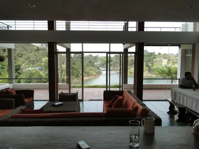a living room with couches and a view of a river at Hotel Familiar El Remanso Del Agua in Guatapé