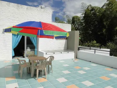 a table and chairs under a colorful umbrella on a patio at Hotel Familiar El Remanso Del Agua in Guatapé