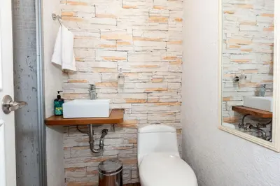 a bathroom with a white toilet and a stone wall at Edificio Casa Roma by Host Medellin in Medellín