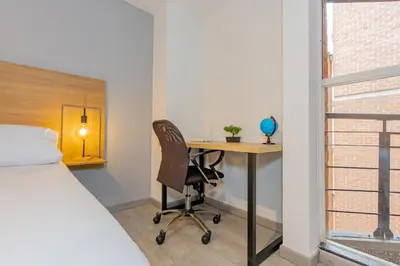 a bedroom with a bed and a desk with a chair at Edificio Casa Roma by Host Medellin in Medellín
