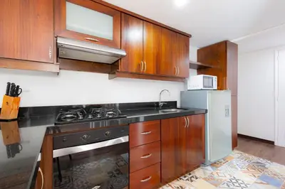 a kitchen with wooden cabinets and a stove and refrigerator at Edificio Casa Roma by Host Medellin in Medellín