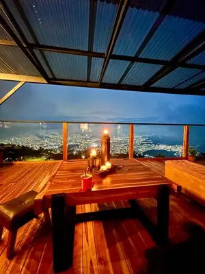 a wooden deck with a table and a view of a city at LP Finca la Pergola, Naturaleza con Lujo y una increíble vista a todo Medellín in Medellín