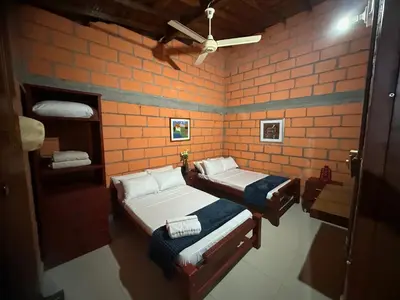 a room with two beds and a brick wall at Finca Hotel Ganadera La Bonita in Cantimplora