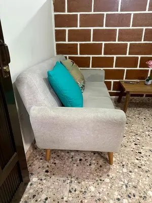 a couch with two blue pillows on it at Cómodo en zona residencial a 1m de Av. el poblado in Envigado